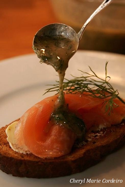 A decadent pour of dill and mustard sauce over gravlax on toast bread.