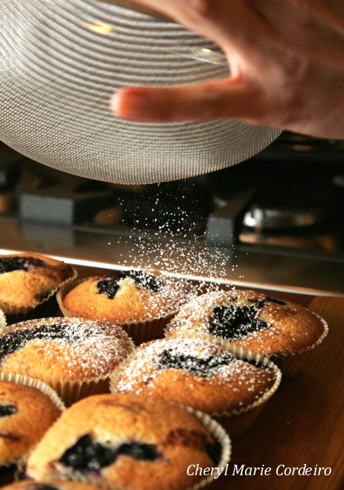Icing sugar on blueberry muffins.