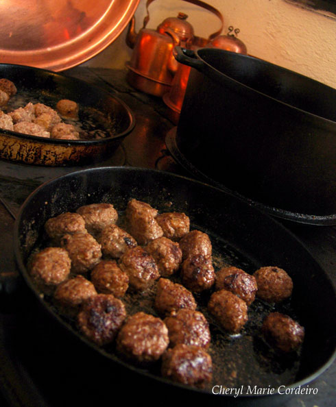 Frying the Swedish meatballs in a cast iron pan using a firewood oven