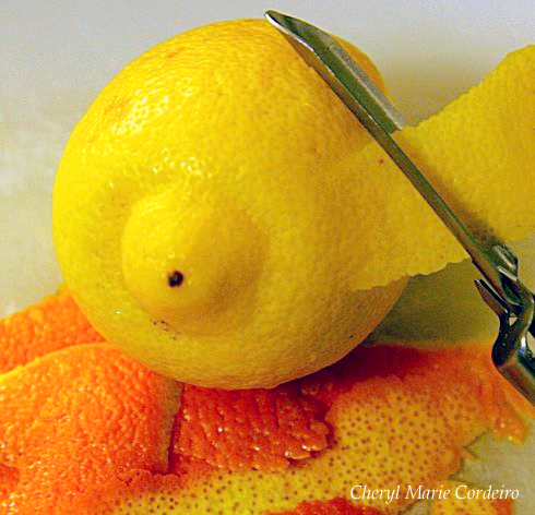 Peeling the zest off a lemon, orange rind in foreground