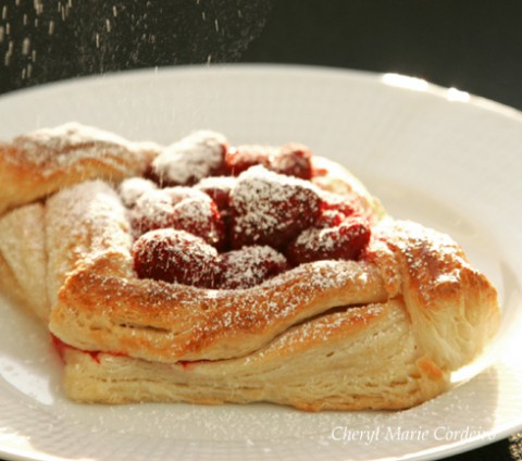 Raspberry danish pastry, dusted with icing sugar on top.