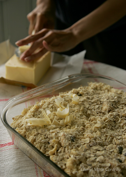 Butter on top of the rolled oats and flour for the apple and banana crumble.