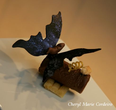 PeChocolate cake petit four with butterfly decoration.