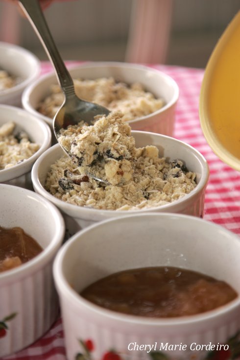 Putting raisin and oat crumble on top of apple sauce.