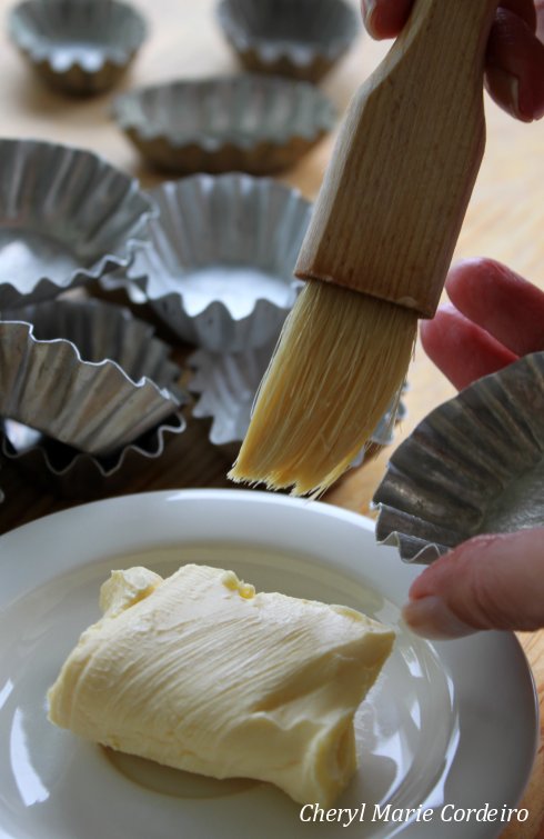 Buttering the tin forms for Swedish mazariner.